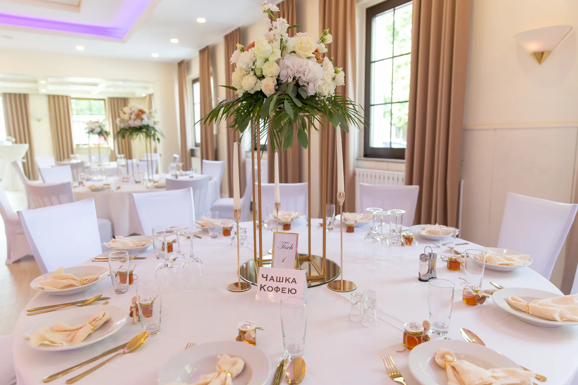 Festlich eingedeckte runde Tafel mit Blumengesteck und Namenskarten